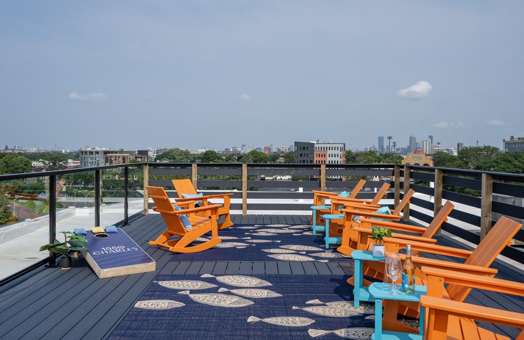 a roof deck with orange adirondack chairs and a view of the city