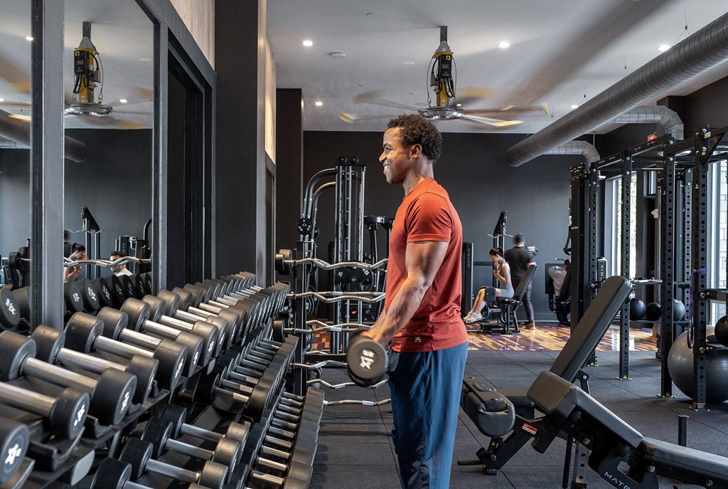 a man standing in a gym holding a dumbbell