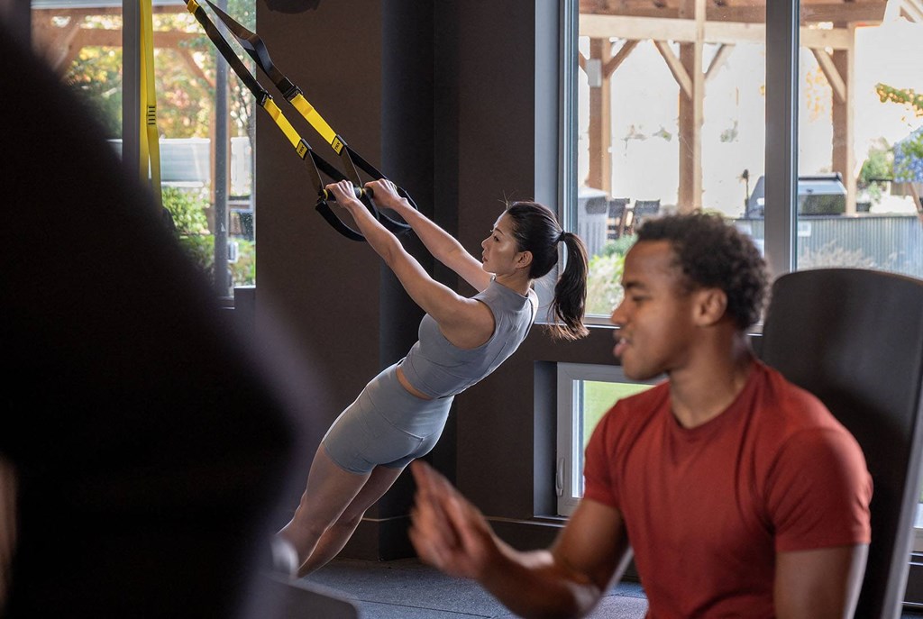 a woman swinging on a rope in a gym while a man watches