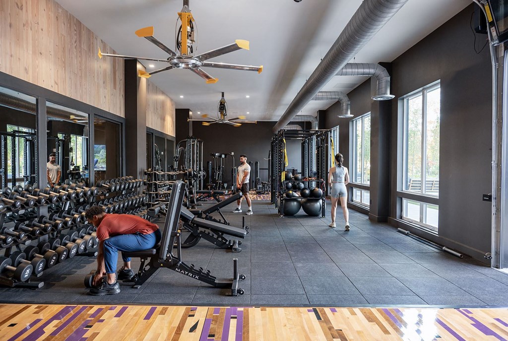people working out in a gym with weights and a ceiling fan