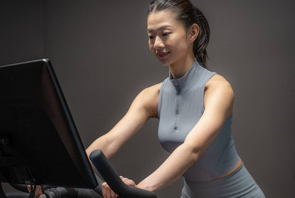 a woman in a gray tank top working on a treadmill
