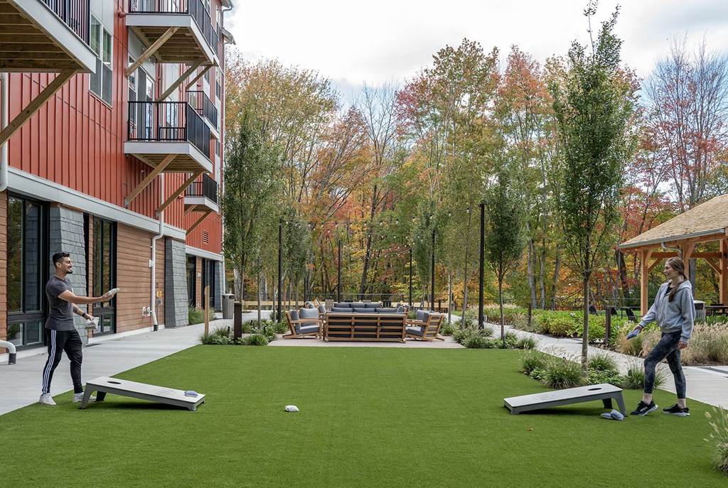 two men playing frisbee on a lawn in front of a building