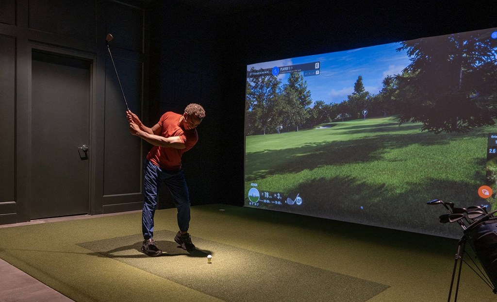 a man swinging a golf club at a ball on a simulator