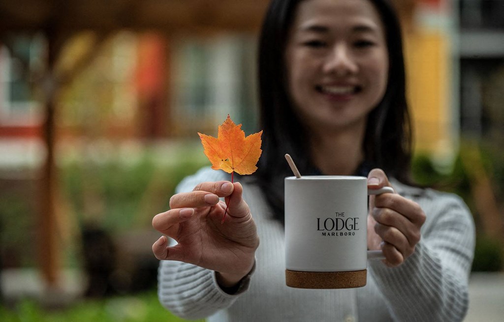 a woman holding a cup of coffee and an autumn leaf