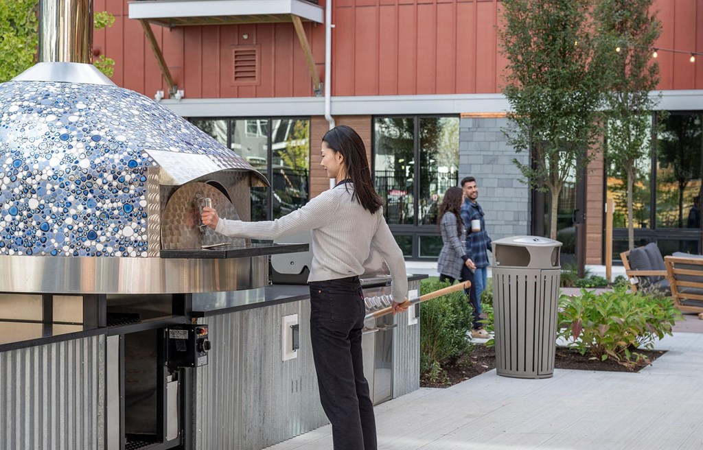 a woman is putting food into a pizza oven