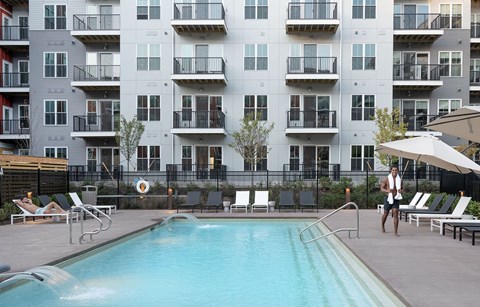 a man standing next to a pool in front of an apartment building