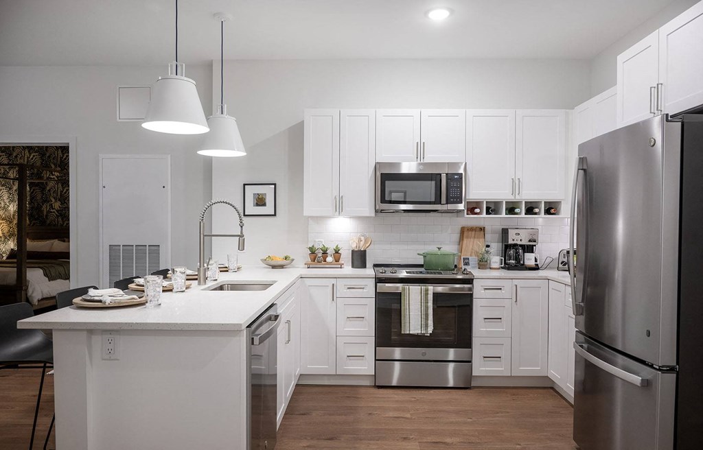 a white kitchen with stainless steel appliances and a white counter top