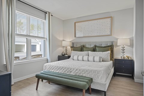 A bedroom with a large bed and a window with curtains.