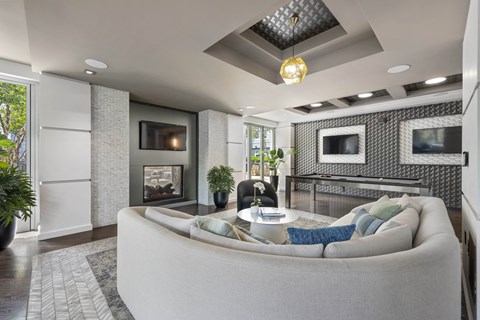A modern living room with a grey couch and a fireplace.