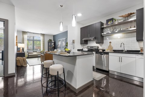 A modern kitchen with a white island and black cabinets.