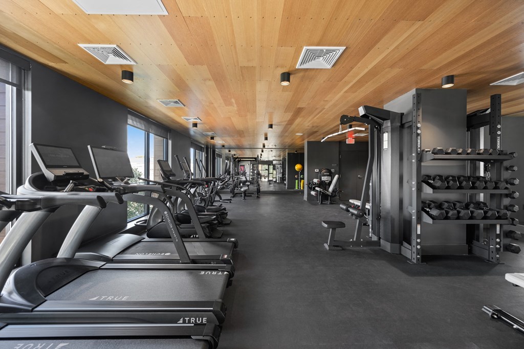 a gym with treadmills and other exercise equipment in a building with wood ceilings