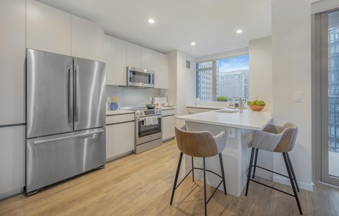 a kitchen with stainless steel appliances and a counter with two chairs