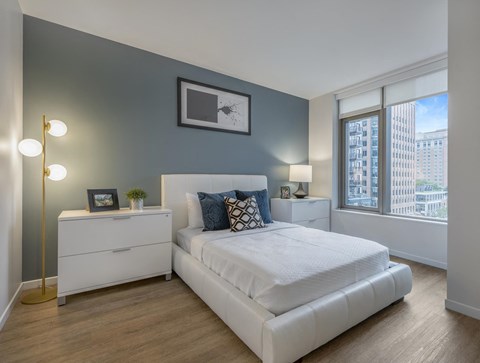 a bedroom with a bed and a dresser in front of a window