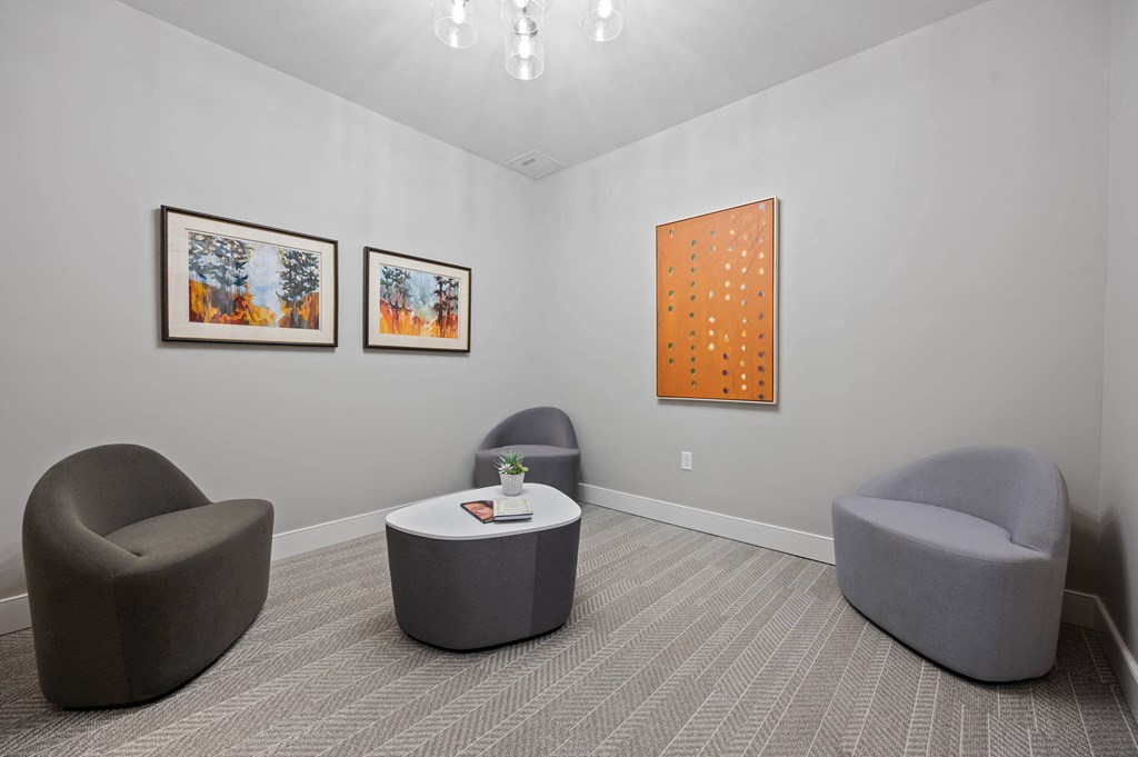 a room with two chairs and a table and paintings on the wall