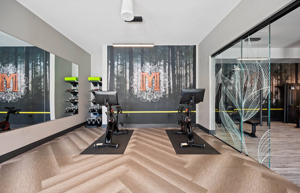 a gym with weights and a wall with a painting of a forest