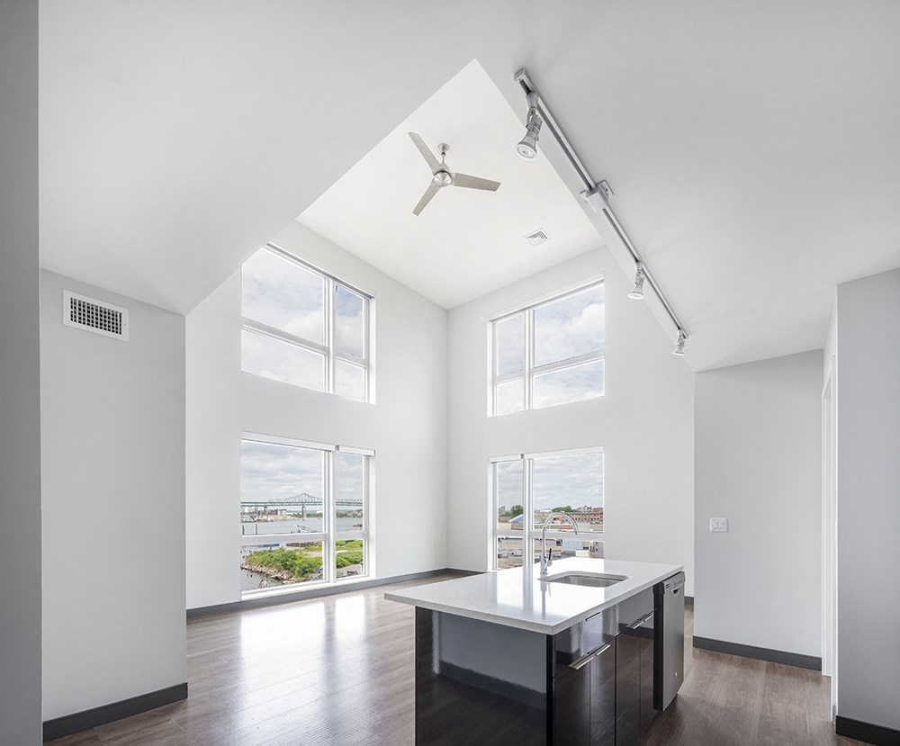 a kitchen with white walls, high loft ceilings, and a large window
