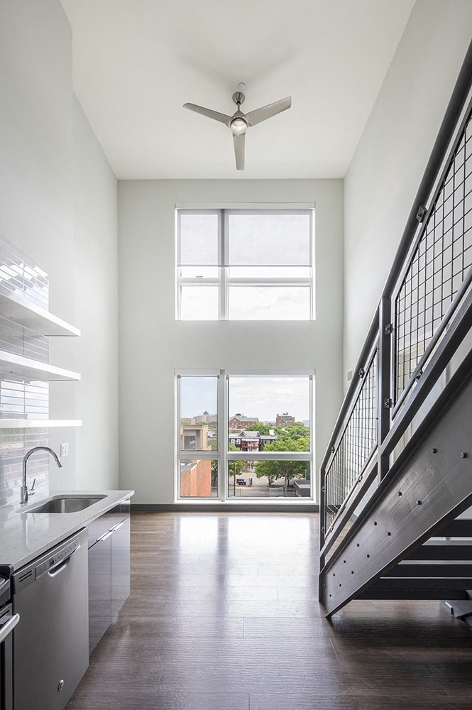 a kitchen with a sink and a staircase and two windows