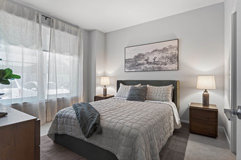 A bedroom with a large bed and a painting on the wall.