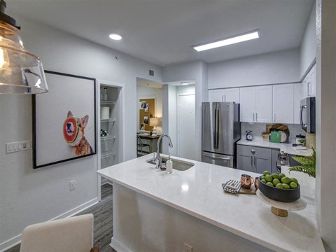 a kitchen with a white counter top and a stainless steel refrigerator