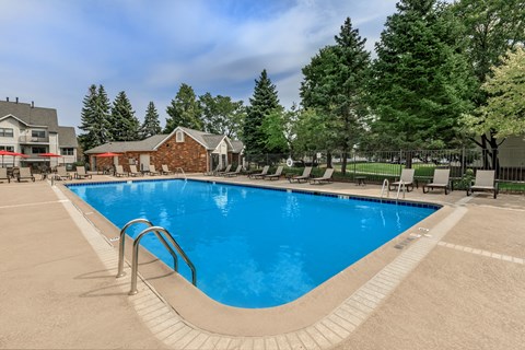 A large outdoor swimming pool surrounded by trees and a building.
