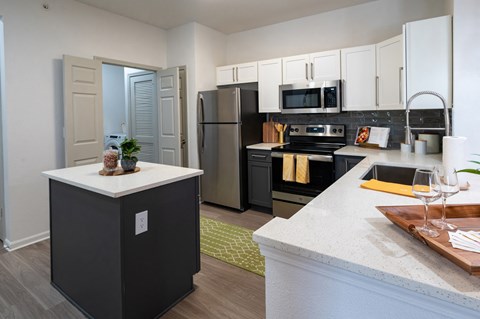 A kitchen with a black refrigerator and a white island.