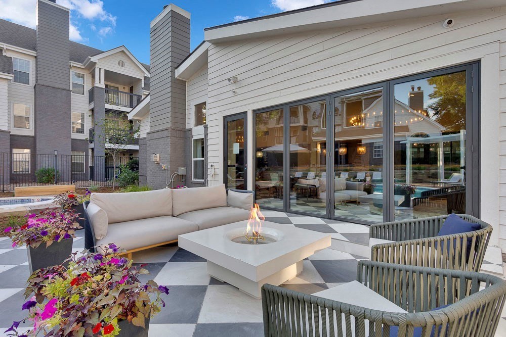 A patio area with a checkered floor, a fire pit, and chairs.