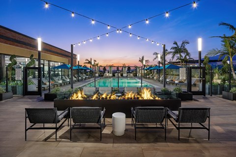 a pool with lounge chairs and a fire pit