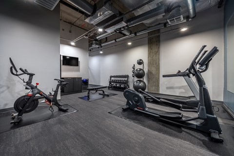 A gym with a stationary bike, rowing machine, and other equipment.