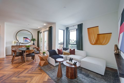 A modern living room with a white sofa, wooden coffee table, and a large abstract painting on the wall.