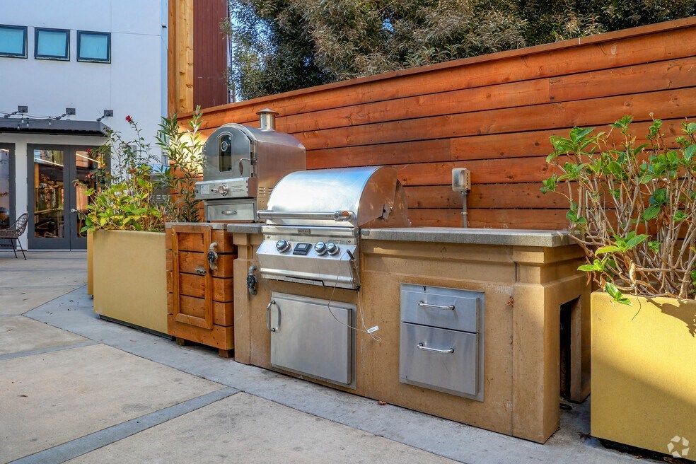 a stainless steel barbecue grill in front of a wooden wall