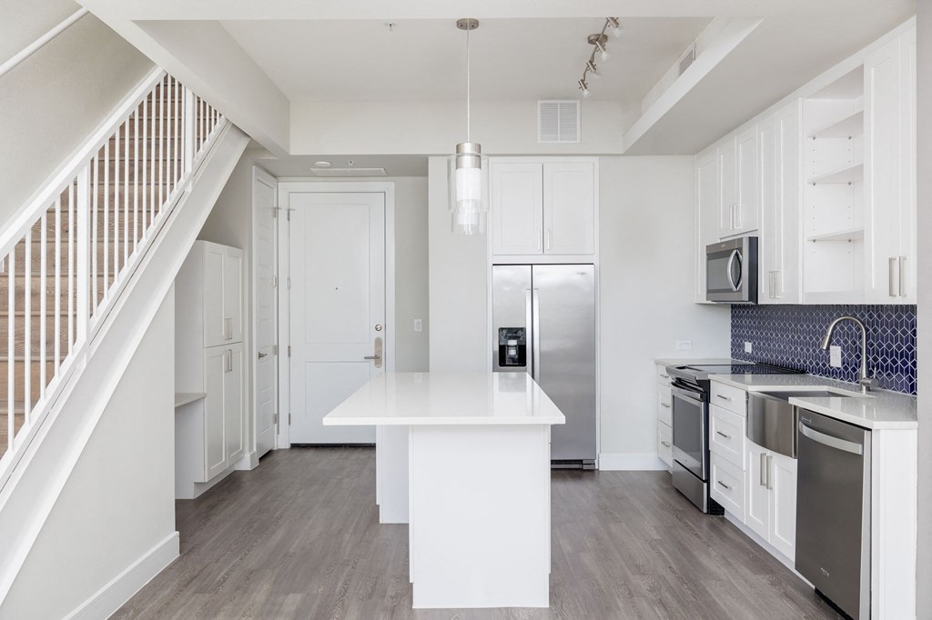 a white kitchen with a white island and stainless steel appliances