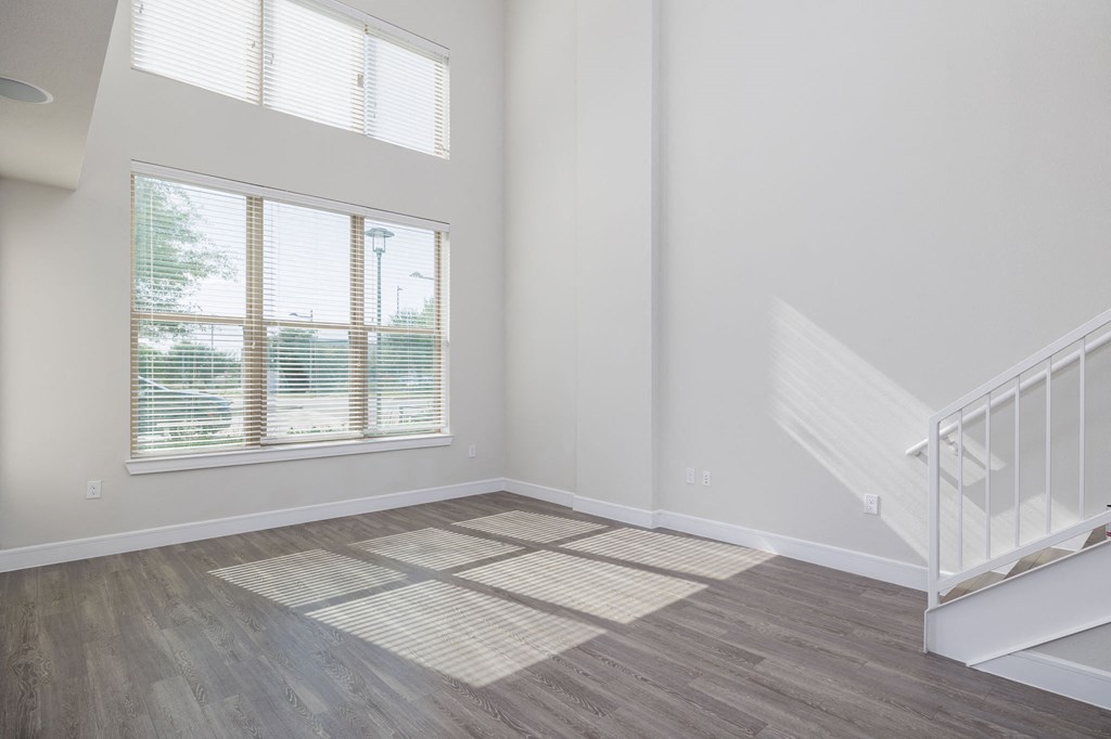 an empty living room with stairs and a window