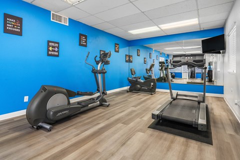 a gym with various exercise machines and a blue wall