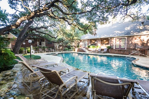 a pool with lounge chairs and a house in the background