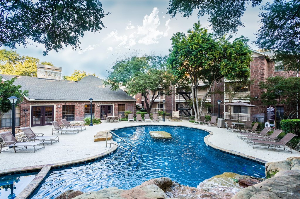 a pool with lounge chairs and trees in the background