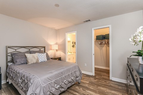 A bedroom with a large bed and a wooden floor.