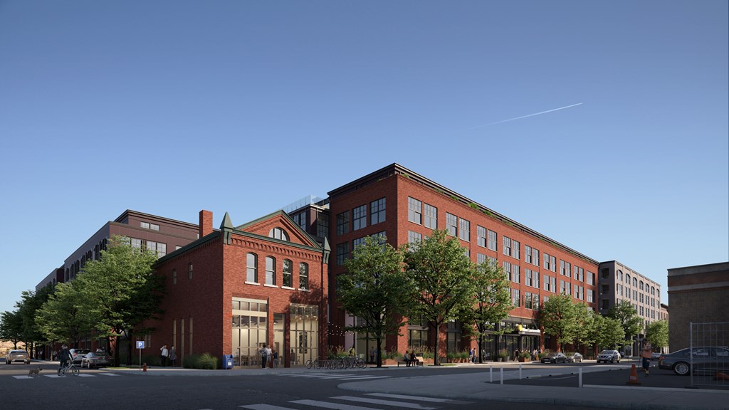 A red brick building with a green roof and a tree in front of it.