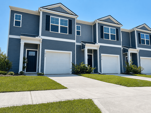A row of houses with garages and front yards.