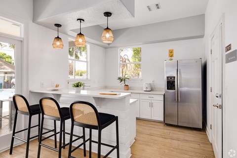 A kitchen with a white counter and black bar stools.