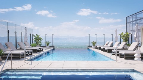 A pool with lounge chairs and a view of the mountains.