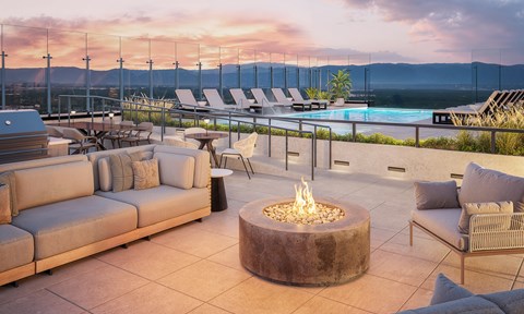A patio with a fire pit and lounge chairs.