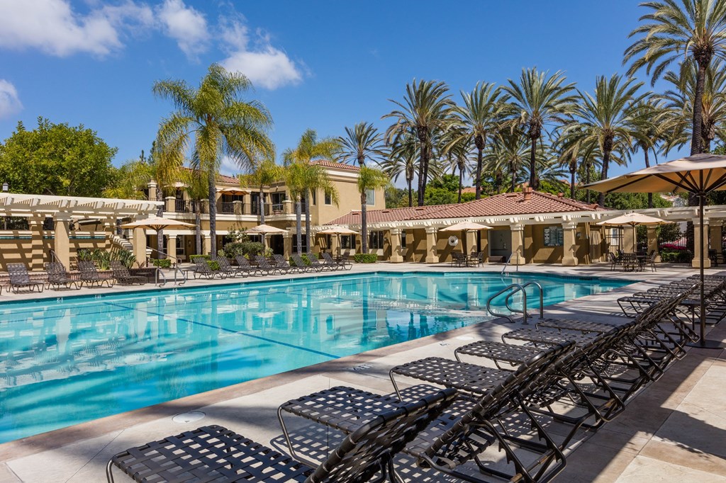 a swimming pool with lounge chairs and umbrellas in front of a hotel