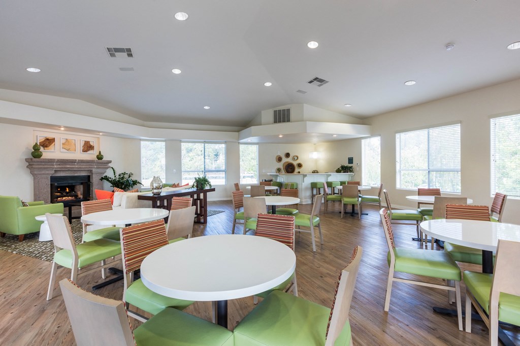a resident clubhouse with tables and chairs and a fireplace