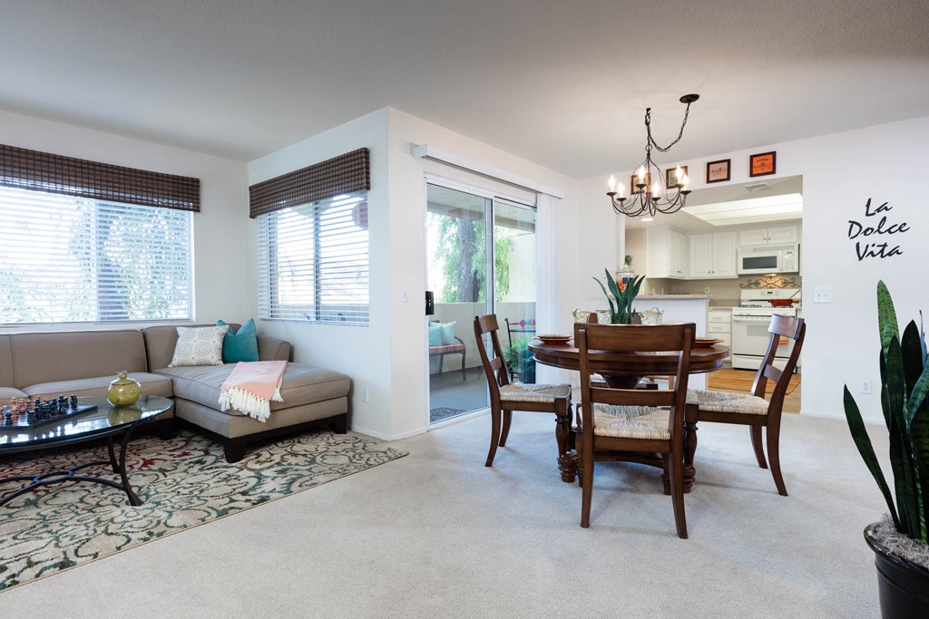 a living room and dining room area with white walls and carpeted flooring