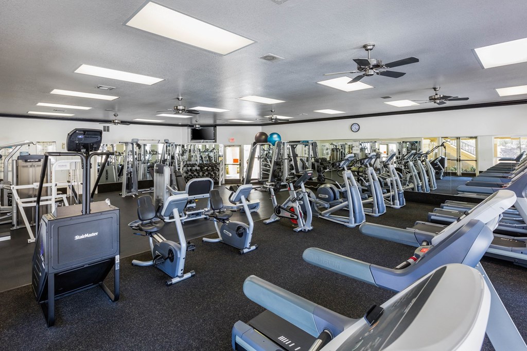 a large fitness room with cardio equipment and weights