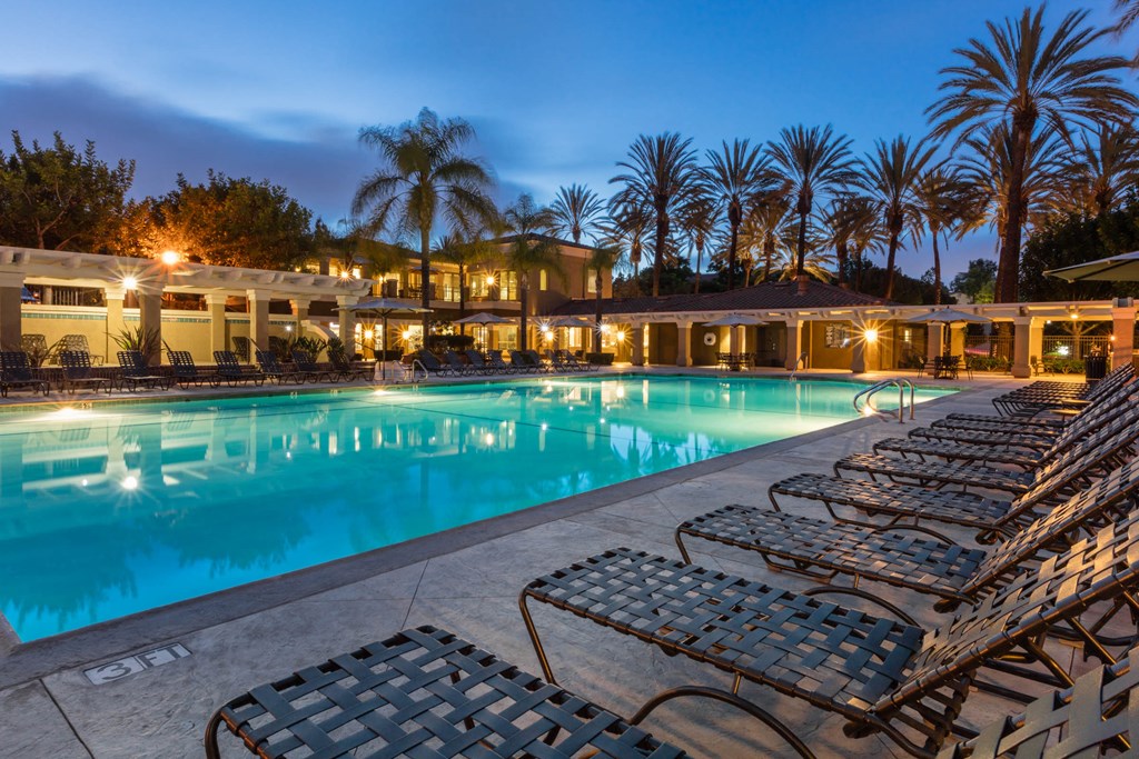 a pool with lounge chairs and palm trees in the background