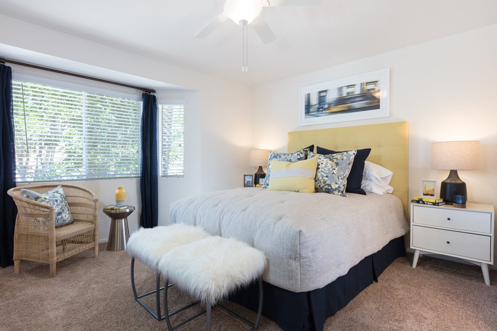 a bedroom with a bed and a chair in front of a window