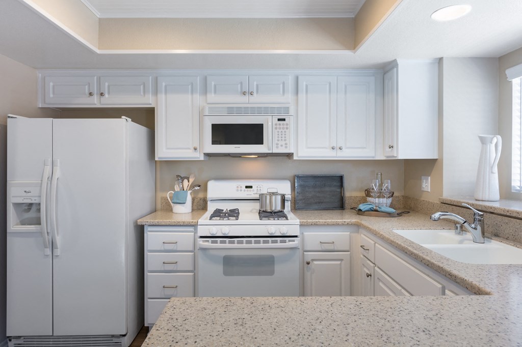 a kitchen with white cabinets and a white stove top oven