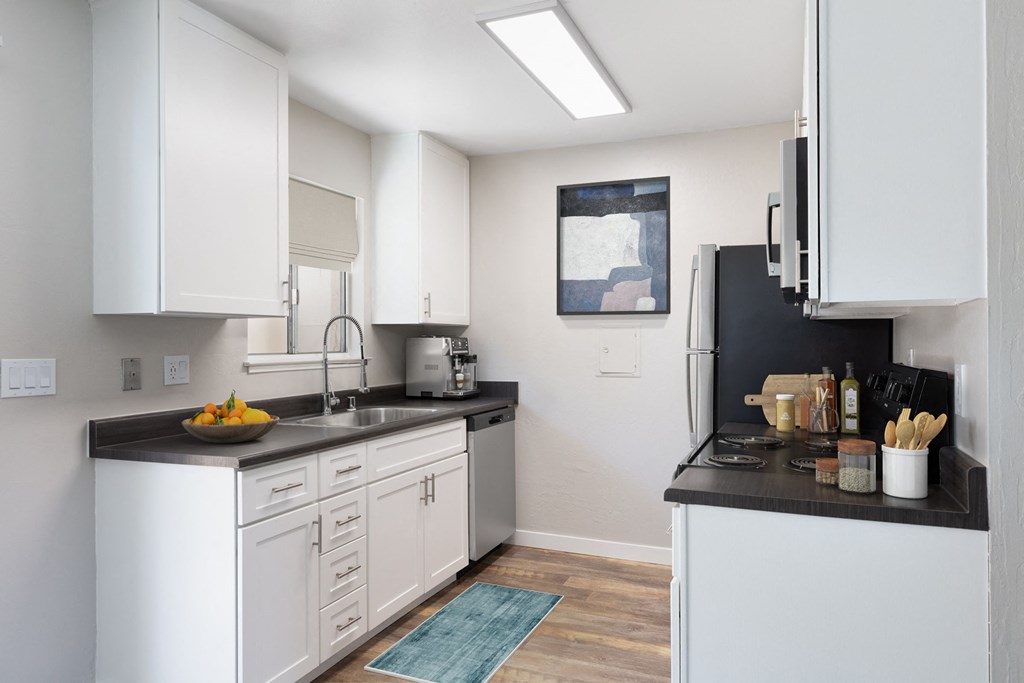 a kitchen with white cabinetry and black countertops