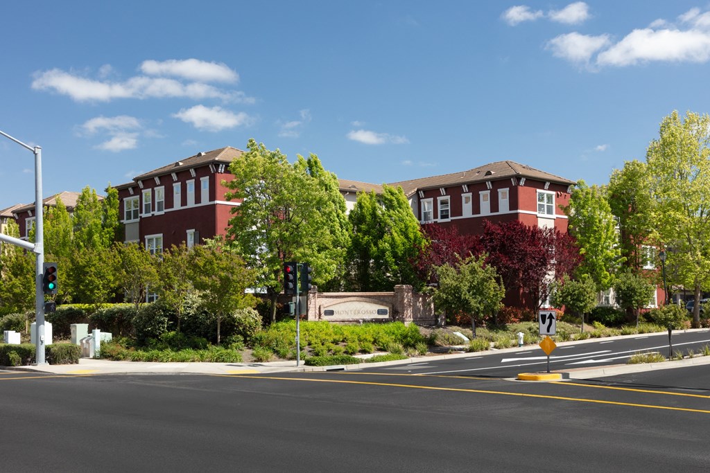 a street corner with two red brick buildings in the background and trees in the foreground